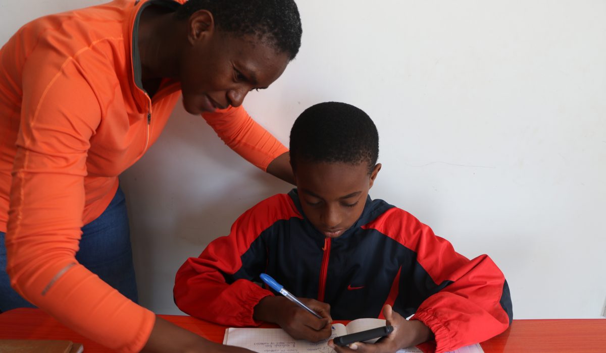 A student works on math problems, guided via SMS by his tutor and assisted by a guardian. Courtesy of ConnectEd.