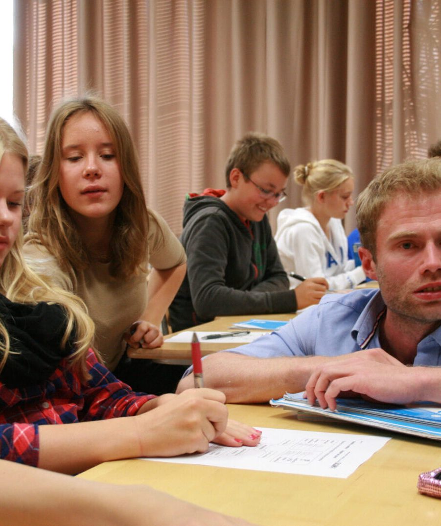 FINLAND - "A pipeline of highly qualified, well-respected teachers in Finland work hard to help all students reach a basic level of achievement by the end of 9th grade." photo by Erin Richards At the Normal Lyceum of Helsinki, English-language teacher Taneli Nordberg helps students with noun-adjective agreement exercises. Nordberg is a product of the selective teacher recruitment and training program at the University of Helsinki.