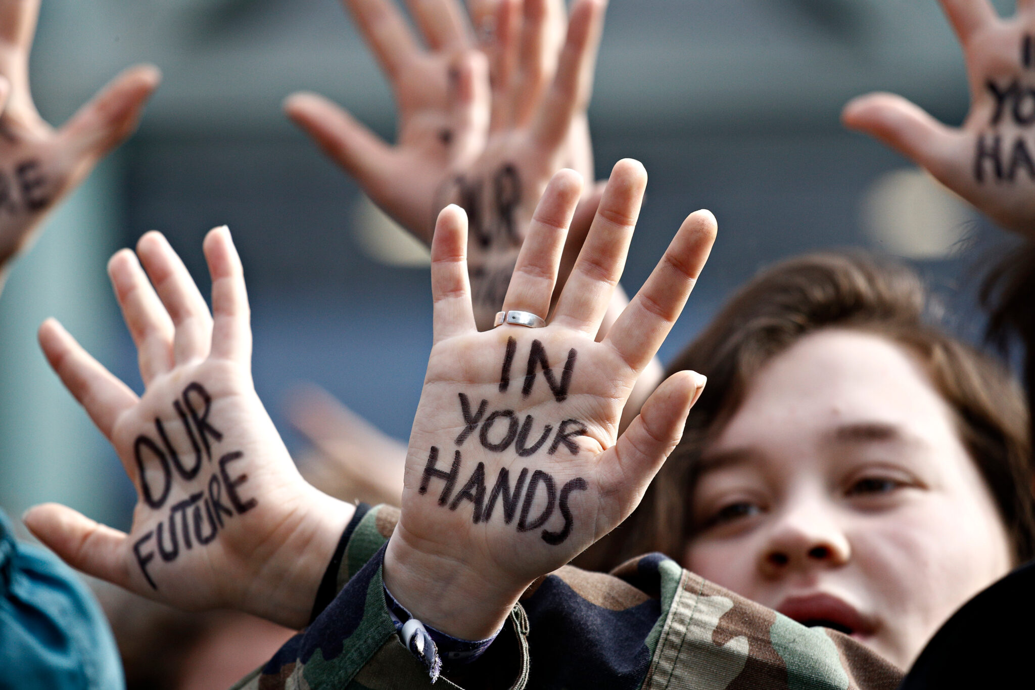 Child at protest with hands that say "our future in your hands"